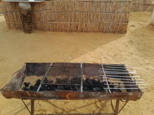 a rusty grill in the middle of a dirt field at Energy camp in Bawati