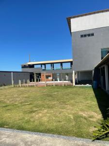 a building with a grass field in front of it at Mansão Xodó in Marataizes