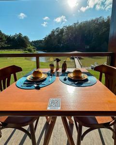 a wooden table with plates and utensils on a balcony at Sítio dos Lagos in Domingos Martins