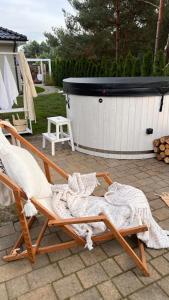 a rocking chair sitting on a patio with a hot tub at Sosenkowe Apartamenty Balia & Jacuzzi in Kuźnica Głogowska