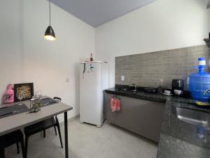 a kitchen with a white refrigerator and a table at Flat Mobiliado no centro in Redenção