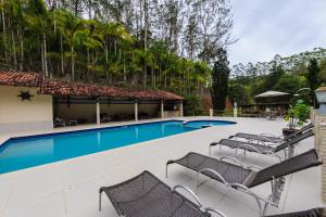 a swimming pool with chairs next to a resort at Sítio dos Lagos in Domingos Martins