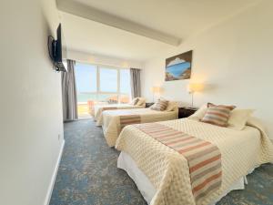 a hotel room with three beds and a window at GRAN PALAZZO Hotel in Villa Gesell