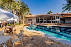 a swimming pool with tables and chairs next to a house at Villa de Holanda Parque Hotel in Holambra