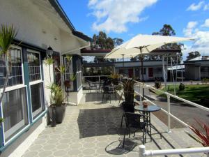 a patio with tables and chairs and an umbrella at The Highlander Motel - 24HR Check In in Maryborough