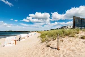a sandy beach with chairs on it next to the water at Aparthotel Ostseeperle Glowe - schön gestrandet in Glowe