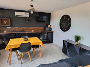 a kitchen with a table and a clock on the wall at Gites de Lenny in Valréas +3 photos