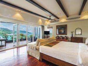 Katamanda - Villa Amanzi by Elite Havens في شاطئ كاتا: غرفة نوم بسرير واريكة ونافذة كبيرة