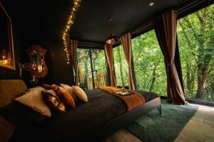 a bedroom with a bed in a room with windows at La Cabane Enchanteresse in Illoud