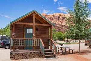 a small cabin with a picnic table in front of a mountain at Sun Outdoors Arches Gateway in Moab