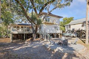 a house with a tree and chairs in front of it at The Ugly Dolphin a Stylish Home for 12 in Edisto Island