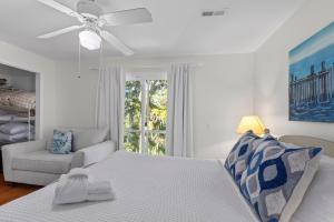 a white bedroom with a bed and a couch and a window at The Ugly Dolphin a Stylish Home for 12 in Edisto Island