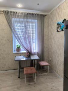 a table and two stools in a room with a window at Апарт-Отель Rozi in Svalyava