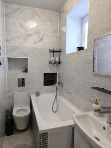 a bathroom with a tub and a toilet and a sink at Апарт-Отель Rozi in Svalyava