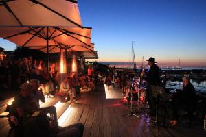 a group of people sitting on a deck with a man on a stage at Weißt Du noch - Gästehäuser & Suiten in Kühlungsborn +123 photos