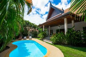 a swimming pool in front of a house at Romanee Villa by G Estate in Rawai Beach