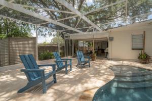 a patio with blue chairs and a table and a pool at Spacious Boho Retreat Heated Pool-HotTub-Huge Yard in Tampa