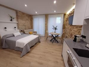 a bedroom with a bed and a table in a room at Apartamentos Porta do Espolón in Noya
