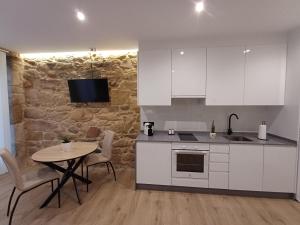 a kitchen with white cabinets and a table with chairs at Apartamentos Porta do Espolón in Noya +20 photos
