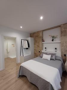 a bedroom with a large bed and a brick wall at Apartamentos Porta do Espolón in Noya