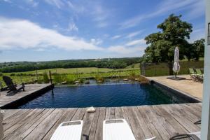 a swimming pool with a wooden deck and chairs at La Gironie in Pomport