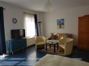 a living room with a couch and a tv at Landhotel Ostseetraum & Apartments in Warnemünde