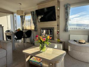 a living room with a vase of flowers on a table at Dolphin View in Llanddwywe