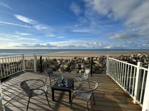 a deck with chairs and a table on the beach at Dolphin View in Llanddwywe