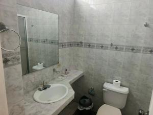 a bathroom with a sink and a toilet and a mirror at OCEANIk SUITES & HOTEL in Guayaquil +26 photos