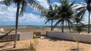 a sandy beach with palm trees and the ocean at Oca Teko Porã in Genipabu