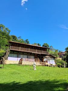 a building with a dog in the middle of a field at Pousada Canto do Papagaio in Aiuruoca
