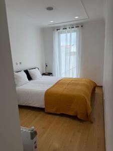 a bedroom with a bed with a yellow blanket on it at Elegant Getaway - Spacious 3 Bedroom Apartment -Lisbon Baixa da Banheira in Lavradio