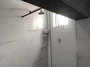 a bathroom with a shower with white marble walls at Seaview Serenity in Gqeberha +17 photos