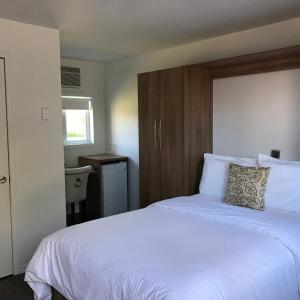 a bedroom with a large white bed with a wooden headboard at Hôtel-Auberge Objectif Santé in Longueuil