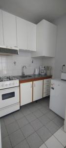 a kitchen with white cabinets and a stove and refrigerator at Dpto del Cerro in Tandil