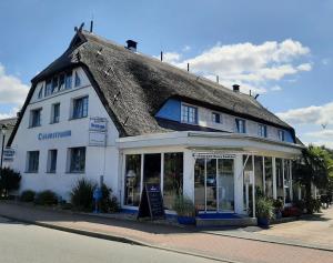 a large white building with a thatched roof at Landhotel Ostseetraum & Apartments in Warnemünde
