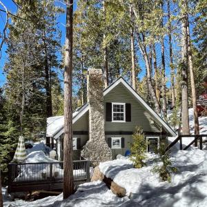 a house with a stone chimney in the snow at The Little Dipper Cabin in Shaver Lake