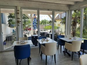 a restaurant with white tables and chairs and windows at Landhotel Ostseetraum & Apartments in Warnemünde