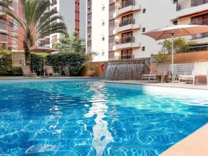 a swimming pool with an umbrella and some buildings at Flat com piscina no Jardim Paulista a 300m da Av Paulista e metrô in São Paulo