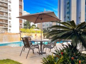 a table with chairs and an umbrella next to a pool at Flat com piscina no Jardim Paulista a 300m da Av Paulista e metrô in São Paulo
