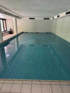 a large swimming pool with blue tiles on the floor at Velmora Boutique Suites - Wellness - Pool, Sauna, E-Bikes direkt am Strand in Timmendorfer Strand