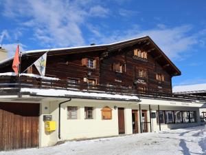 a large wooden building with snow on the roof at Ski- und Berghaus Obergmeind in Tschappina