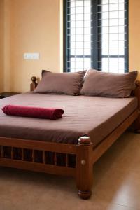 a bed with a red pillow on top of it at Casa Tangerina in Varkala