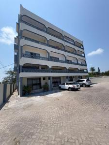 a large building with two cars parked in front of it at Shanzu Studio Stamford Apartment in Mombasa
