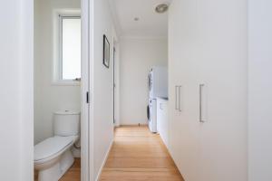 a white bathroom with a toilet and a sink at Evergreen by the Bay in Sandringham +17 photos