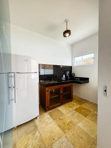 a kitchen with a white refrigerator and a counter at Pousada Vila Didi - Flats com Cozinha Completa in Barra Grande
