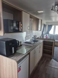 an rv kitchen with a sink and a microwave at Lyon's Robin Hood Rhyl 8 Berth Caravan in Rhyl