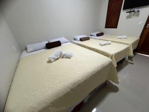 a room with three beds with towels on them at Chalé Rota Das Dunas in Barreirinhas