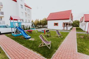 a playground with chairs and a slide in a yard at Domki Heaven Ustronie Morskie in Ustronie Morskie