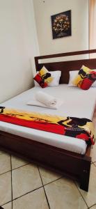 a bed with a wooden frame with a blanket on it at Shanzu Studio Stamford Apartment in Mombasa